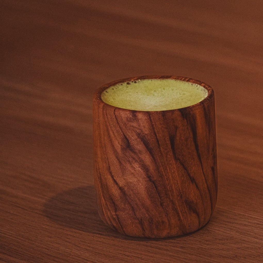 Wooden cup with a matcha tea on a wooden surface