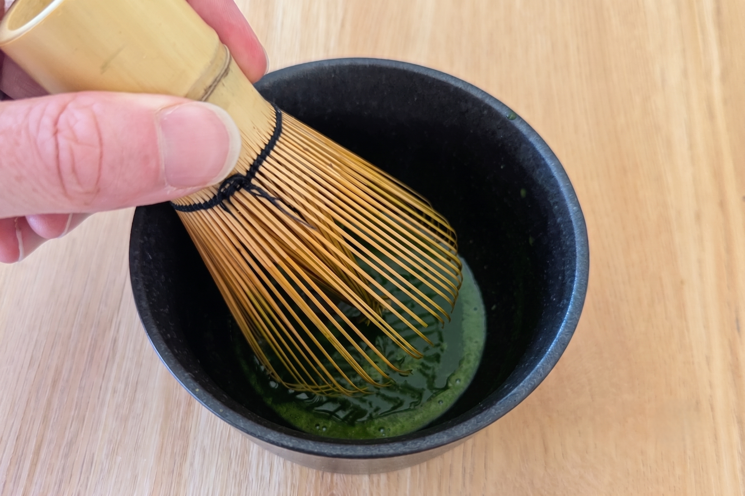 Preparing a matcha latte by whisking the matcha in a chawan