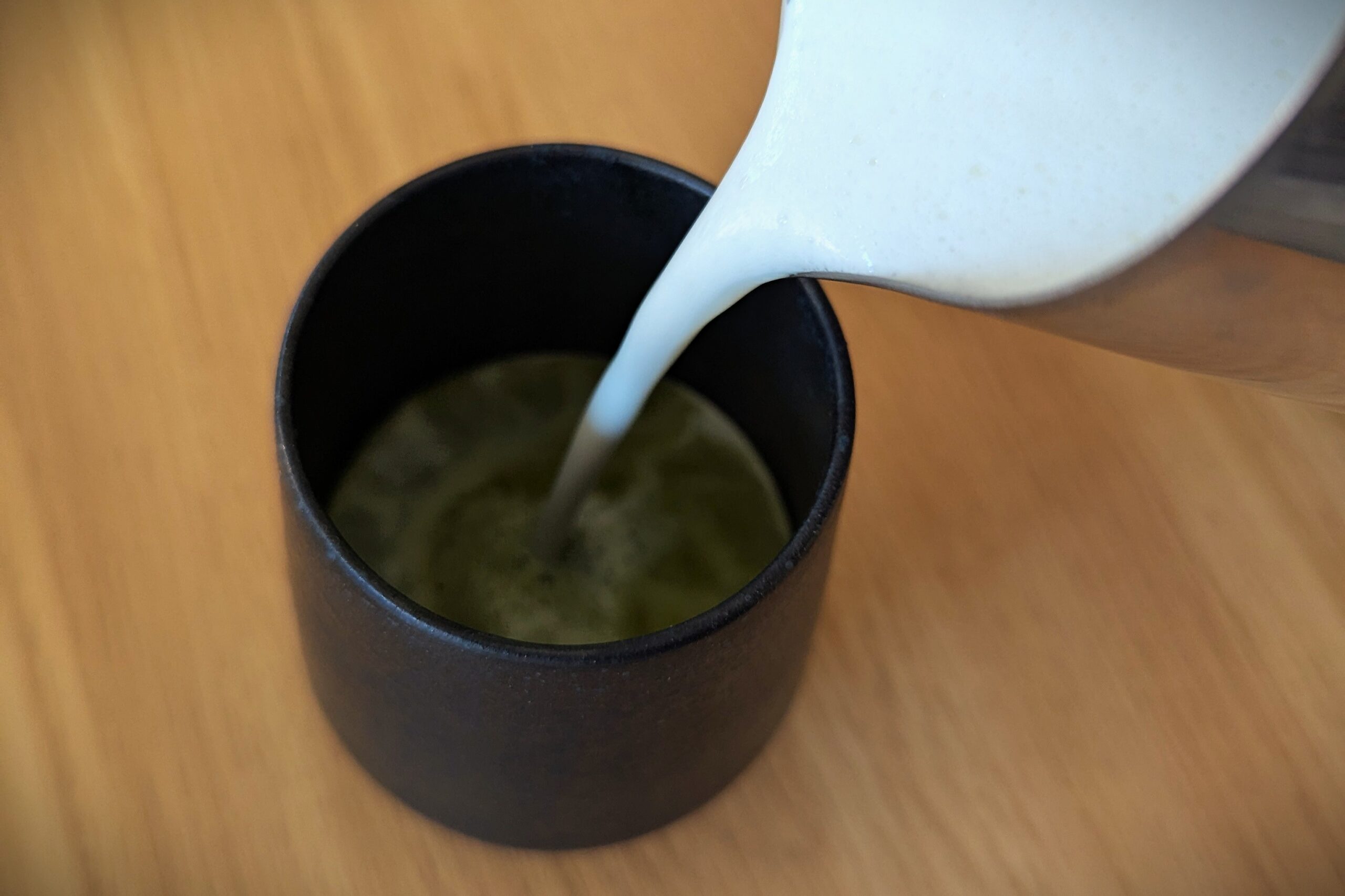 Pouring foamed milk into a matcha latte